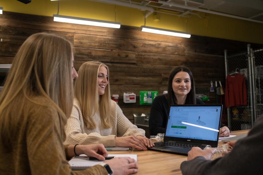 Three female students collaborating around a desk.